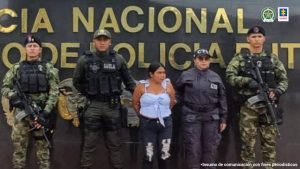 En la imagen se ve una mujer detenida bajo custodia de integrantes de la Policía Nacional.