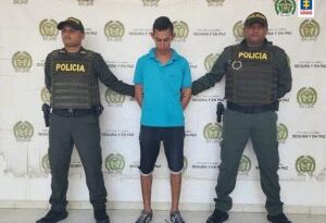 En la fotografía aparece un hombre capturado, acompañado de dos uniformados de la Policía. En la parte posterior un banner con logos de la entidad.