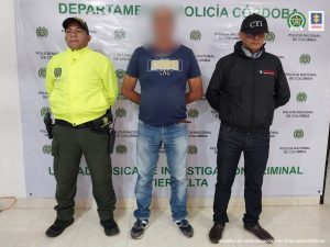 En la imagen se ve una persona detenida entre un uniformado de la Fiscalía y uno de la Policía