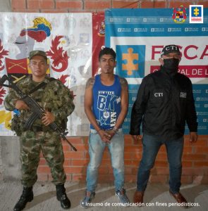 en la imagen se ve una persona detenida bajo custodia de integrantes del CTI y del Ejército. Detrás suyo backings institucionales.