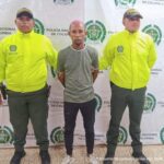 En la fotografía se observan tres personas, dos uniformados de la Policía y el capturado. En la parte posterior se observa un backing con escudos de la Policía Nacional.