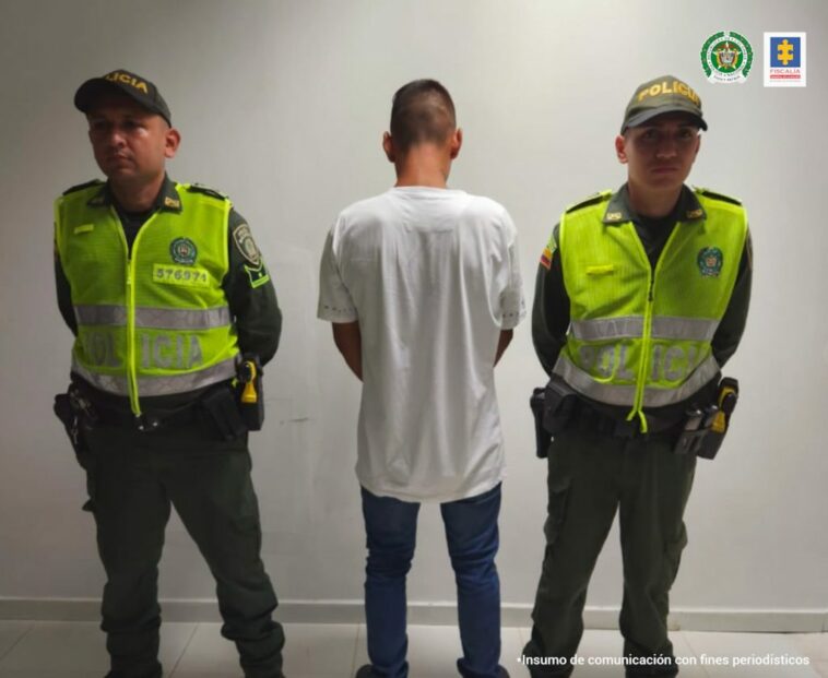 en la imagen se ve una persona detenida de espaldas bajo custodia de dos uniformados de la Policía Nacional.