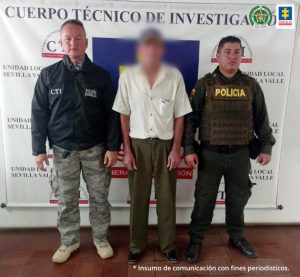 En  la fotografía se aprecia a Laureano Torrejano Figueroa, de pie. Viste camisa de manga corte color beage; pantalón café y zapatos oscuros; asimismo, usa gorra. Al lado derecho de él hay un uniformado del CTI de la Fiscalía y a la izquierda hay un uniformado de la Policía Nacional. Detrás de ellos hay un pendón institucional con logos del CTI y de la Fiscalía.