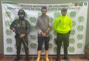 En la imagen se aprecia al capturado junto a dos uniformados de la Policía y Ejército Nacional: Detrás se visualiza el banner que identifica al Departamento de Policía de Norte de Santander
