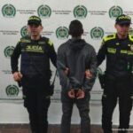 En la imagen se ve una persona detenida, de espaldas, entre dos uniformados de la Policía Nacional.