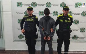 En la imagen se ve una persona detenida, de espaldas, entre dos uniformados de la Policía Nacional.