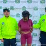 En la foto aparece Jeniffer Andrea Mosquera Córdoba con dos policías a los lados y atrás el pendón de la Policía Nacional.
