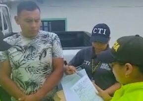 : en la imagen se ve una persona detenida a quien una integrantes de la Policía le lee sus derechos como capturado. También es acompañado por una investigadora del CTI.