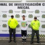 En la fotografía se aprecia a Juan Manuel Galindo Lenis, de pie y con los brazos atrás. Viste camiseta de manga corta blanca con estampado de colores verde y naranja; pantalón de sudadera negro con blanco y zapatillas negras con blanco. A lado y lado de ellos hay uniformados de la Policía Nacional y Detrás de ellos hay un pendón institucional de la Policía.