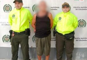 Dos uniformados de la Policía Nacional custodian al presunto agresor de 71 años de edad.