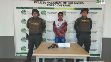 En la fotografía aparece el capturado junto a dos uniformados de la Policía Nacional. Frente a ellos una mesa con el arma y munición incautada. En la parte posterior el banner que identifica a la Estación de Policía de Tame (Arauca)