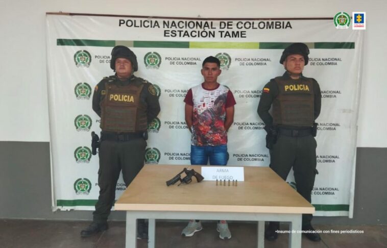 En la fotografía aparece el capturado junto a dos uniformados de la Policía Nacional. Frente a ellos una mesa con el arma y munición incautada. En la parte posterior el banner que identifica a la Estación de Policía de Tame (Arauca)