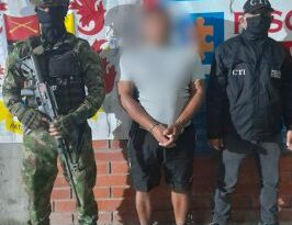 en la imagen se ve una persona detenida bajo custodia de un investigador del CTI y un integrante del Ejército.