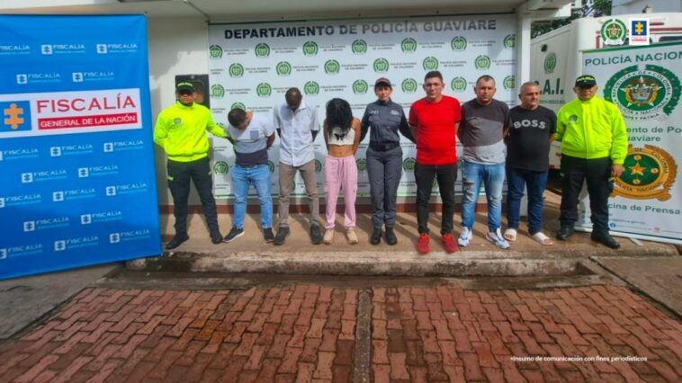 capturados de frente custodiados por policías. Detrás banner de Policía y Fiscalía.