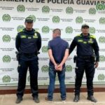 Padrastro imputado por la Fiscalía por el delito de actos sexuales con menor de 14 años agravado. Texto Alternativo: capturado de espaldas custodiado por dos policías. Detrás banner de la Policía Nacional.