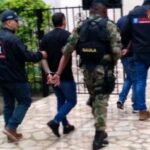En la foto se aprecia a  Cristian Andrés Millán Ramírez y José Luis Grueso Solís, en acción de caminata, con los brazos atrás, esposados y conducidos por personal uniformado del CTI de la Fiscalía y del Gaula Ejército.