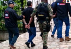 En la foto se aprecia a  Cristian Andrés Millán Ramírez y José Luis Grueso Solís, en acción de caminata, con los brazos atrás, esposados y conducidos por personal uniformado del CTI de la Fiscalía y del Gaula Ejército.