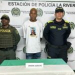 En la foto se aprecia de pie a  Jetli David Quijano. Viste camiseta blanca con estampado multicolor del rostro de un hombre, a la altura del pecho; asimismo, jean azul.  A lado y lado de ella hay uniformados de la Policía Nacional. Delante de ellos hay una mesa con mantel de colores blanco y verde y sobre ella hay un letrero que dice: ‘Orden judicial’. Detrás de ellos hay un pendón institucional de la Policía.