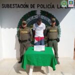 En la fotografía aparece un hombre capturado, en compañía de dos uniformados de la Policía Nacional. En la parte posterior un logo de la entidad.