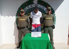 En la fotografía aparece un hombre capturado, en compañía de dos uniformados de la Policía Nacional. En la parte posterior un logo de la entidad.