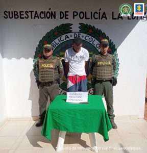 En la fotografía aparece un hombre capturado, en compañía de dos uniformados de la Policía Nacional. En la parte posterior un logo de la entidad.