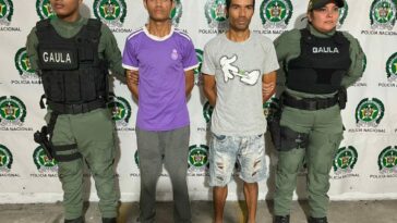 Los dos presuntos extorsionistas son custodiados por dos agentes de la Policía Nacional tras materializar su captura en flagrancia.