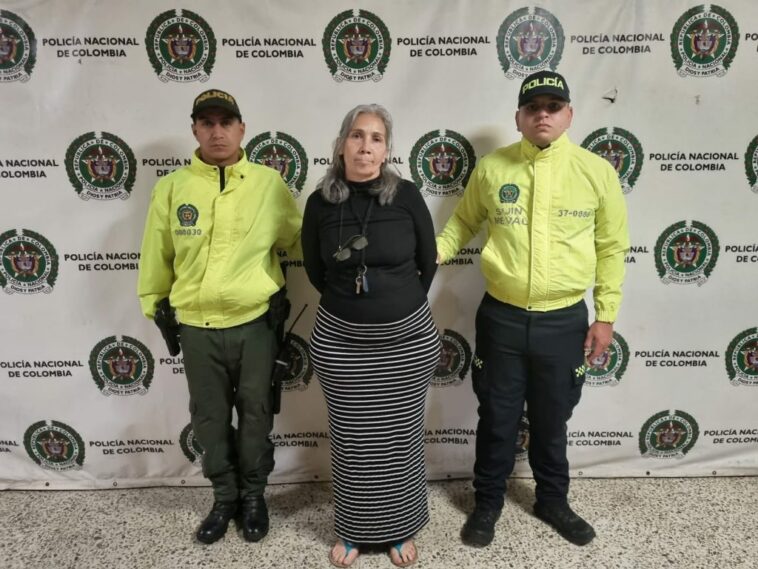 En la foto aparece una mujer con pelo canoso y en medio de dos uniformados de la Policía Nacional.