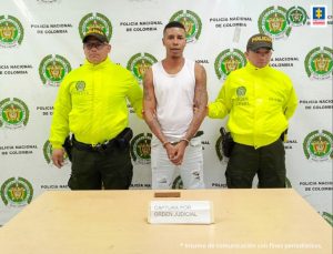 En la fotografía aparece el capturado junto a dos agentes de la Policía Nacional. En la parte superior se observa un banner de la Policía Nacional