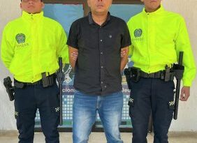 En la fotografía aparece una persona capturada, acompañado de dos uniformados de La Policía. En la parte posterior un banner con logos de la entidad