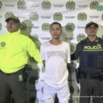 Stiben Alonso Vargas Barrera, alias Tatuaje, acompañado a los lados por funcionarios de la Policía Nacional y atrás el pendón de la Policía Nacional.