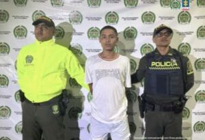 Stiben Alonso Vargas Barrera, alias Tatuaje, acompañado a los lados por funcionarios de la Policía Nacional y atrás el pendón de la Policía Nacional.