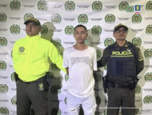 Stiben Alonso Vargas Barrera, alias Tatuaje, acompañado a los lados por funcionarios de la Policía Nacional y atrás el pendón de la Policía Nacional.