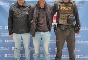 En la fotografía aparece el capturado junto a un servidor del CTI y un agente de la Policía Nacional. En la parte superior está un banner de la Fiscalía General de la Nación