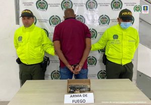 Se visualiza al capturado de espaldas, junto a dos uniformados de la Policía Nacional. Frente a ellos el arma de fuego tipo pistola que le hallaron al momento de la captura. Detrás de ellos se ubica el banner que identifica a la Policía Nacional. 

 4 archivos adjuntos
  •  Analizado por Gmail
