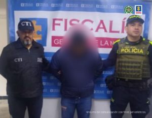 En la fotografía aparecen el capturado junto a un servidor del CTI y un agente de la Policía nacional. En la parte superior está un banner de la Fiscalía General de la Nación