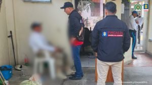 En la fotografía están dos funcionarios del CTI de la Fiscalía conversando con el capturado que se encuentra sentando en una silla en la puerta de las instalaciones de la Fiscalía de Cartagena.