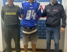 José Alejandro Guapacha Barco acompañado a los lados por funcionarios del CTI y la Policía Nacional y de fondo el pendón de la Fiscalía.