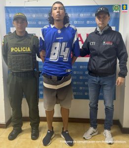 José Alejandro Guapacha Barco acompañado a los lados por funcionarios del CTI y la Policía Nacional y de fondo el pendón de la Fiscalía.
