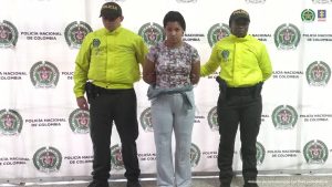 En la fotografía está Luisa Fernanda Lopera Flórez, mujer condenada por homicidio de un extranjero, con dos servidores de la Policía Nacional