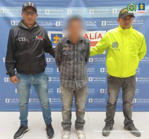 En la fotografía aparece el capturado junto a un servidor del CTI y un agente de la Policía Nacional. En la parte superior se observa un banner de la Fiscalía General de la Nación