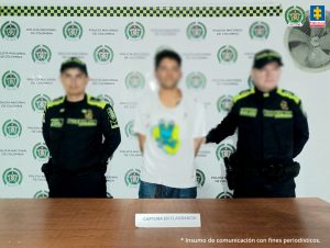 En las tres fotografías se observa al capturado en el centro y a cada costado un uniformado de la Policía Nacional.  Atrás un pendón de  Policía Nacional y delante una mesa en la cual está expuesto el material incautado.