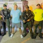 En la fotografía aparece un hombre capturado, acompañado de uniformados de La Policía y el Ejército Nacional.  En la parte posterior un banner con logos de la entidad.