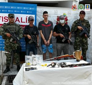 En la imagen se ve una persona detenida bajo custodia de integrantes del CTI y del Ejército. Frente a él una mesa con sustancia estupefaciente y otros elementos incautados.