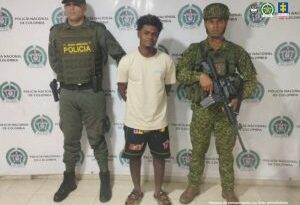 En la fotografía aparece el capturado junto a un agente de la Policía Nacional y un infante de la Armada Nacional. En la parte superior está un banner de la Policía Nacional