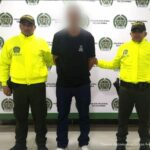 El capturado aparece de frente a la cámara, está vestido de negro y con sus manos esposadas a la espalda, lo custodian dos uniformados de la Policía Nacional.