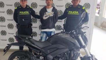 En la imagen está el procesado con dos servidores de la Policía Nacional y la motocicleta incautada en la parte delantera
