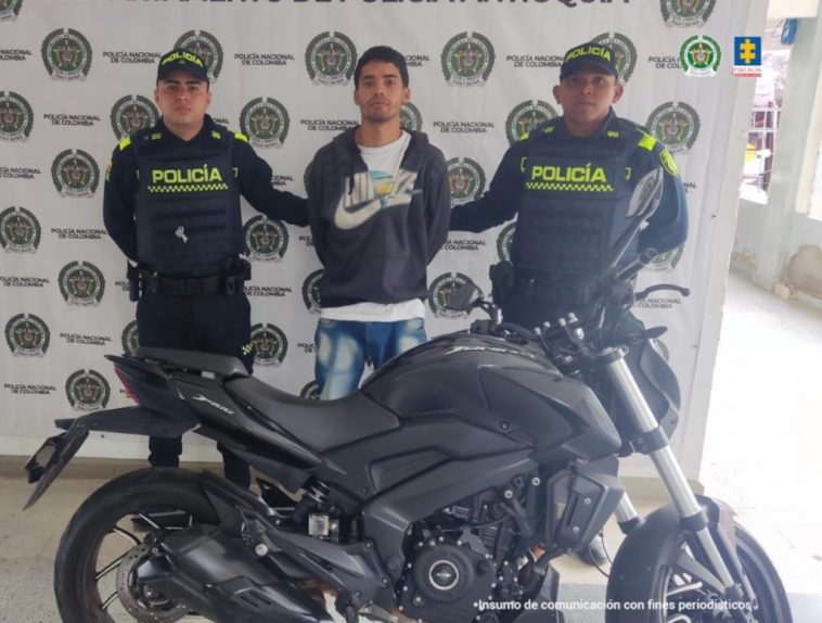 En la imagen está el procesado con dos servidores de la Policía Nacional y la motocicleta incautada en la parte delantera