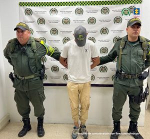 en la imagen se ve un hombre detenido bajo custodia de dos integrantes de la Policía Nacional.