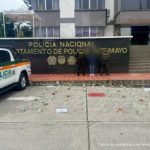 La procesada se encuentra en custodia por dos uniformados de la Policía Nacional. En la foto se observa parte de la munición incautada. Detrás se observa un backing de la Policía.