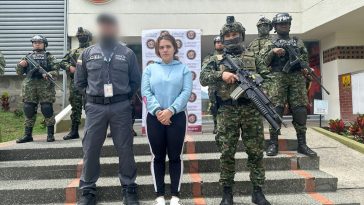 La mujer capturada aparece en el centro de la imagen, sobre unas escaleras y en medio de miembros del Ejército y el CTI de la Fiscalía. Al fondo se ve el letrero "comando Octava Brigada".